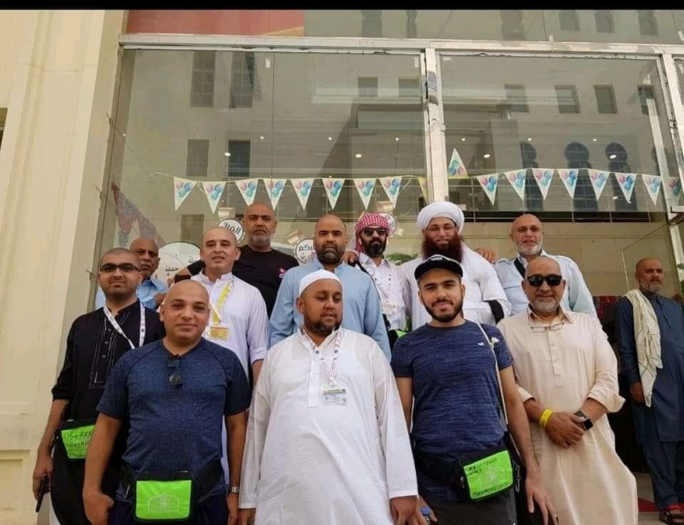 Pilgrims posing near the Makkah directional signage