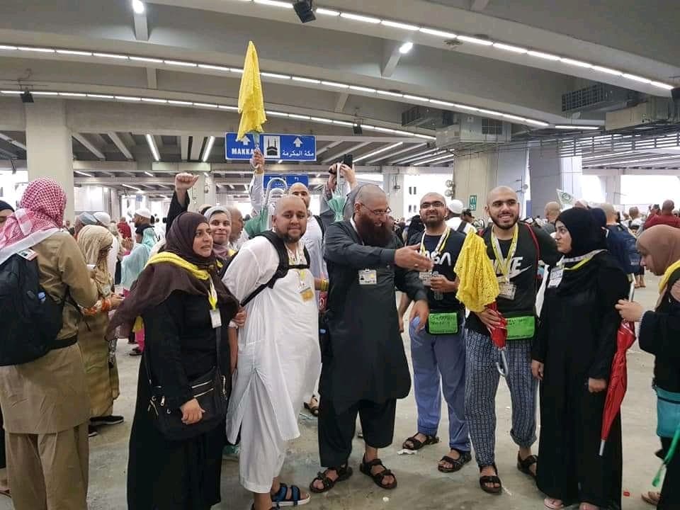 Pilgrim group gathered under the Makkah directional signs